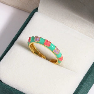 Detail of mint green enamel flower ring with gold plating on white velvet box