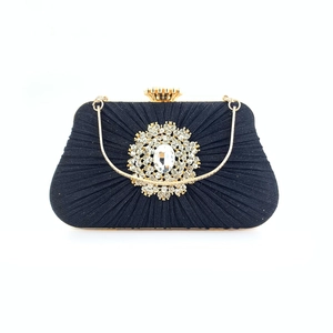 Detail view of black pleated evening bag with large sparkling crystal rhinestone flower