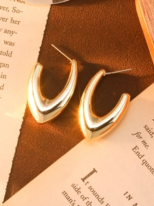 Detailed macro view of gold V-shaped irregular metal earrings with polished mirror finish