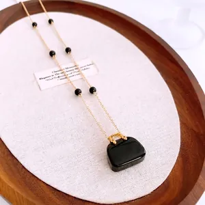 Collana lunga con perline dorate vintage francese e ciondolo a borsa nera lucida