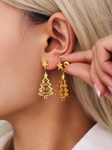 Close-up of golden Christmas tree earrings with stars on a model for a festive look