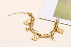 Detail of gold double-layer chain bracelet with square poker card pendant and steel beads