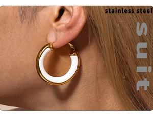 Close-up of wide gold-plated stainless steel C-shape hoop earrings with white enamel