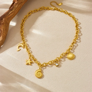 Gold plated stainless steel necklace with dolphin and seashell charms on sandy texture