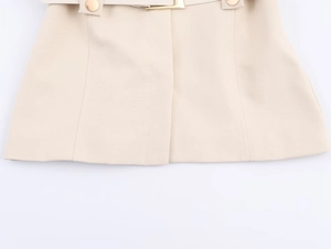 Detailansicht eines beigen Blazers aus Webstoff mit edlen goldenen Metallschnallen