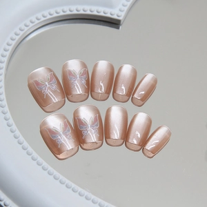 Elegant champagne cat eye press-on nails with butterfly design on a vanity mirror
