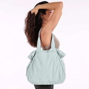 Waterproof 18L yoga tote bag in pale blue-green nylon shown with model for gym and leisure