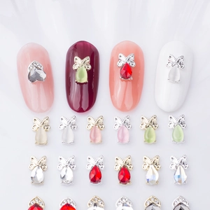 Detailed view of cat-eye heart and bow nail charms with multi-color crystal gemstones