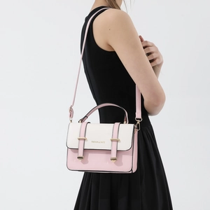 Pink and white contrast shoulder bag with gold hardware worn by a model in black dress
