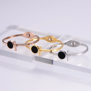 Three minimalist T-clasp bangles in gold rose gold and silver with black enamel detail