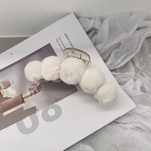 Macro shot of white plush fur hair claw clip against a minimalist lifestyle background