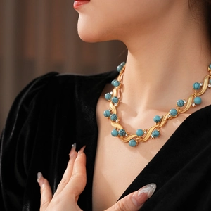 Close-up of vintage gold necklace with turquoise beads and sparkling rhinestones on a model