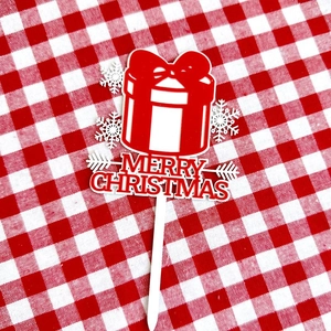 Macro detail of red Merry Christmas acrylic cake topper with white snowflake gift box