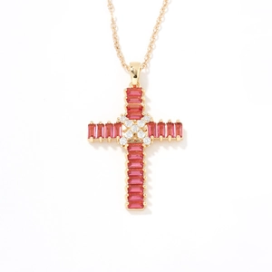 Close-up of golden cross pendant featuring pink rectangular stones and white accents