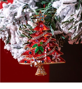 Detailed view of red enamel Christmas tree brooch with rhinestones on a festive pine branch