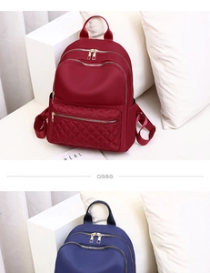 Detalle de mochilas de nailon acolchado en rojo y marino con cremalleras doradas