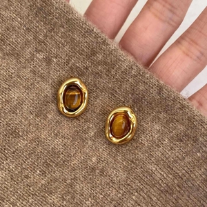 Detailed view of vintage gold-plated oval stud earrings with polished brown tiger eye stone