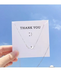 Detailed close-up of a silver peace bird pendant with sparkling diamonds and a thank you card