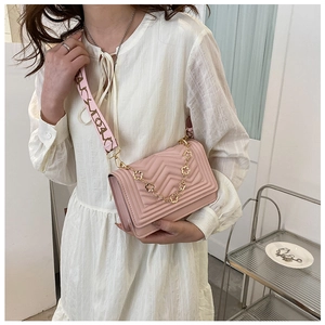 Pink quilted shoulder bag detail featuring floral chain and decorative strap