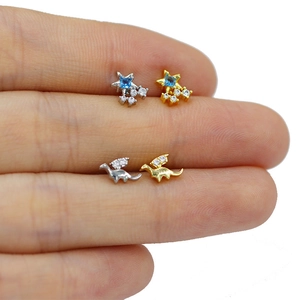 Detail view of gold and silver star and dinosaur studs with blue and clear zircon gems