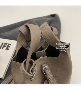 Détail du sac à main en cuir texturé avec boucles argentées et poignée de transport
