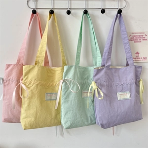 Row of colorful canvas tote bags in pastel pink, yellow, mint green, and lavender purple