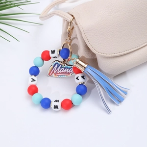 Detail showing Mama silicone bead bracelet with blue tassel on a beige handbag