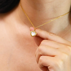 Detailed close-up of retro 18k gold heart pendant with iridescent white shell inlay