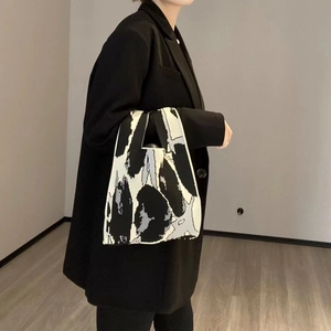 Detail of knit handbag featuring black and white abstract patterns on fabric material
