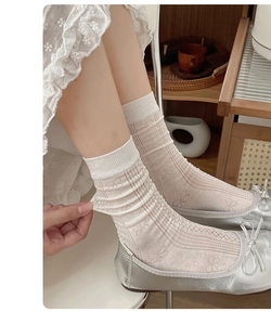 Close-up of semi-transparent beige crew socks with bow jacquard and breathable texture