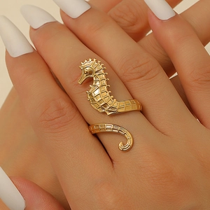 Detail of golden seahorse open ring with textured engraving on a model hand