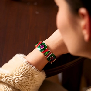 Close-up of vintage gold bracelet with green and red enamel and purple round gemstones