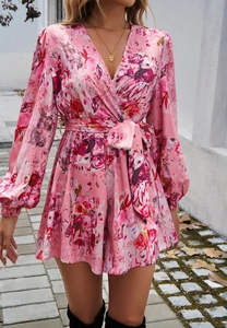 Dettaglio di una tutina a fiori rosa con scollo a V, fiocco in vita e maniche lunghe all'aperto