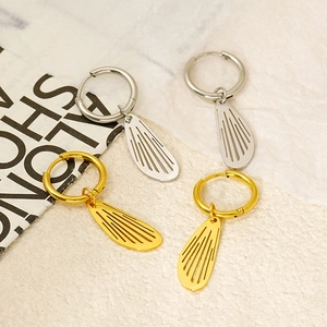 Macro view of gold and silver hollow wing charms on stainless steel hoop earrings