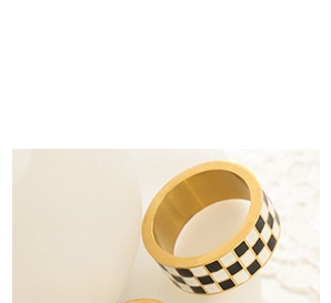 Detail of wide 18K gold plated bangle featuring a classic black and white checkerboard pattern