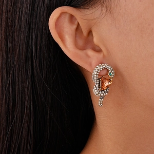 Close-up of luxury snake earring with gold plating, amber teardrop stone and crystals