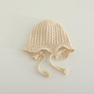 Close-up of cable knit texture and soft lining on a beige baby bonnet with earflaps