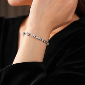 Dettaglio del bracciale in argento a forma di X con pietre di zircone blu e bianche