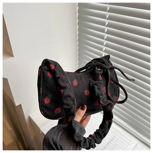Close-up of black corduroy bag with red strawberry embroidery and natural hand hold