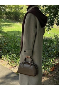 Detail showing army green woolen coat with matching dark hooded scarf and leather bag