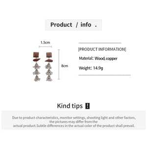 Detail view of ethnic square wood earrings with silver tiered hollow tassel bells