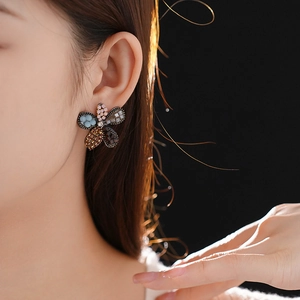 Close-up of five-petal flower earring with colorful beads on a model's ear