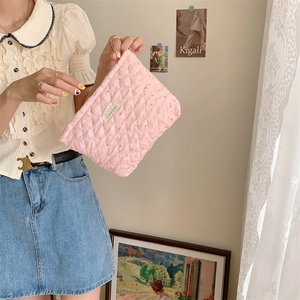 Detailed close-up of pink quilted fabric texture and cute pattern on a travel makeup bag