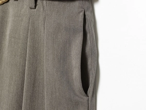 Gros plan sur un pantalon en sergé gris montrant les poches et les plis de la taille