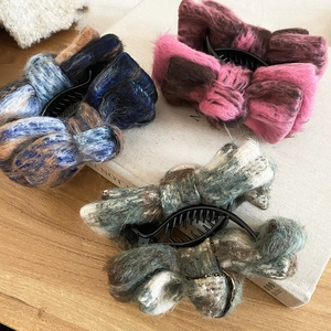 Detailed view of three warm flocked velvet bow hair clips on a wooden tabletop