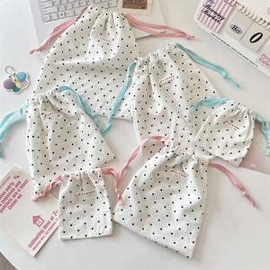 Detailed set of white polka dot drawstring bags in three sizes for organized storage