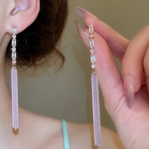 Close-up of gold chain tassel earrings with pink heart zircons and pearls on ear