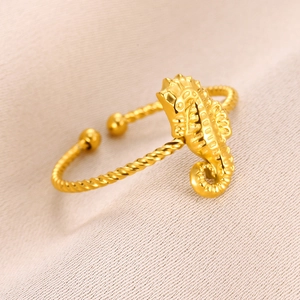 Gold seahorse open ring with twisted rope band design on light pink fabric background