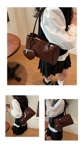 Close-up of vintage brown leather shoulder bag with matching heart-shaped charm accessory