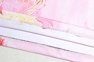 Macro detail of high-density overlock stitching and pink floral pattern on elastic fabric
